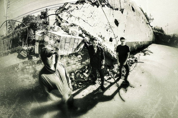 a black-and-white photo of a group of people from rock band shadowplay standing in front of a pile of rubble