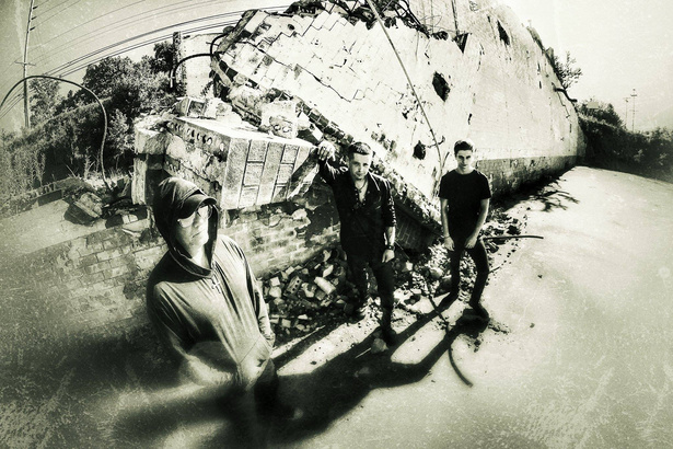 a black and white photo of a group of people from rock band shadowplay standing in front of a pile of rubble