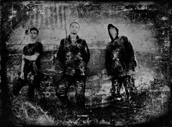a black and white photo of shadowplay members of the rock group standing in front of a brick wall