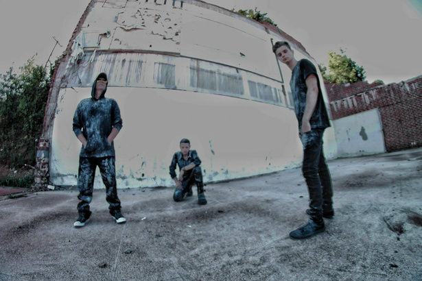 photo of three members from rock industrial band shadowplay are standing in front of a building